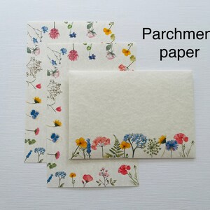 May include: Three sheets of parchment paper with a floral design. The paper is cream colored with a border of blue, yellow, pink, and green flowers. The text "Parchment paper" is printed in black at the top of the image.
