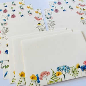 May include: Set of six blank stationery cards with floral designs. The cards feature watercolor illustrations of various flowers in shades of blue, pink, yellow, and green. The cards are perfect for writing letters, notes, or invitations.