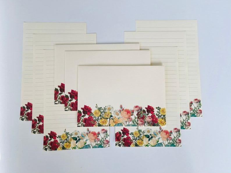 Puede incluir: Un juego de 10 hojas de papeler&iacute;a floral con un borde de flores rojas, rosas y amarillas. Las hojas est&aacute;n rayadas y tienen un fondo crema.