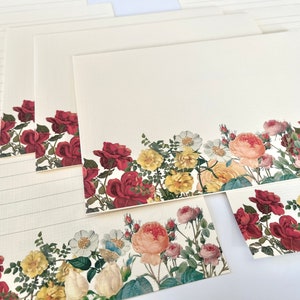 Puede incluir: Conjunto de papeler&iacute;a con un borde floral de rosas rojas, rosas y amarillas, junto con hojas verdes y flores blancas. El papel tiene espacio de escritura rayado.