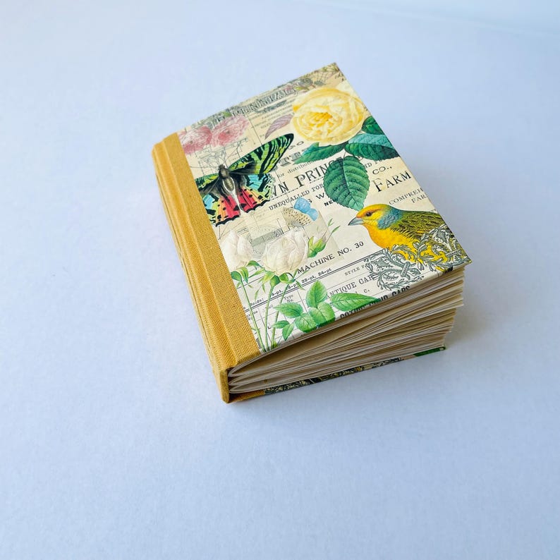 May include: A yellow and white journal with a floral and butterfly design. The cover features a yellow bird, a butterfly, and a yellow rose. The text on the cover reads "N PRING CO. FARM COMPREH PAR".