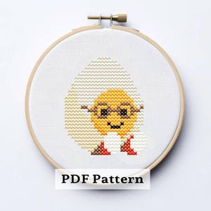 May include: Cross-stitch embroidery of a smiling egg character wearing glasses, set in a wooden hoop. The egg is yellow and white, with brown and red accents. The text "PDF Pattern" is at the bottom.