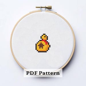 Puede incluir: Un diseño de punto de cruz de una bolsa de dinero amarilla con un lazo rojo, sobre tela blanca dentro de un bastidor de bordado de madera. El texto "PDF Pattern" está visible. Ideal para los fanáticos de los videojuegos.