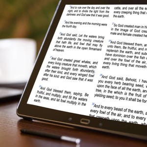 May include: A digital tablet displaying text from the Bible. The screen shows multiple verses with a focus on creation. The tablet is black with a thin bezel, and a stylus is visible at the bottom.