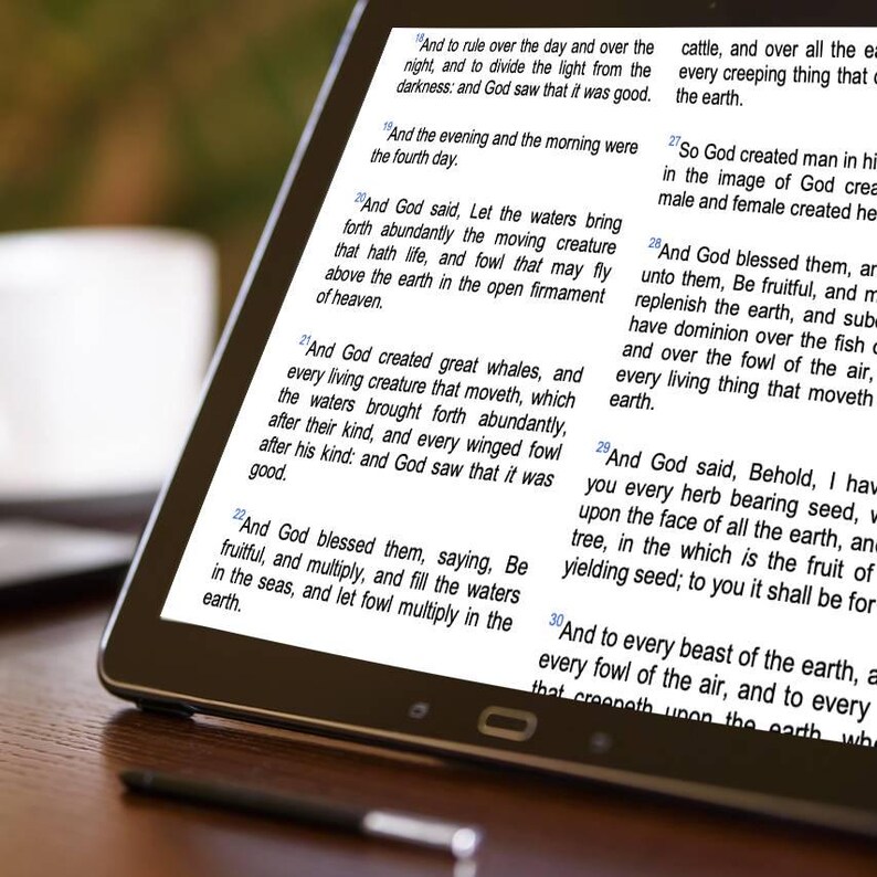 May include: A digital tablet displaying text from the Bible. The screen shows multiple verses with a focus on creation. The tablet is black with a thin bezel, and a stylus is visible at the bottom.