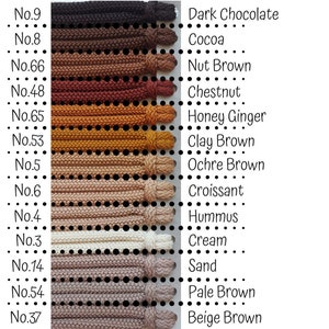 Może przedstawiać: Tabela kolorów 12 różnych odcieni brązowej przędzy, od ciemnej czekolady do beżowego brązu. Każda próbka przędzy jest oznaczona numerem i opisową nazwą, np. "Kakao", "Brąz orzechowy" i "Krem".