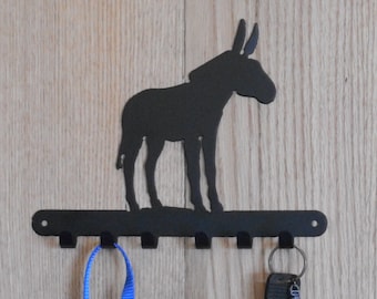 May include: Black metal key rack shaped like a donkey with five hooks. Two blue lanyards and a set of keys are hanging on the hooks.
