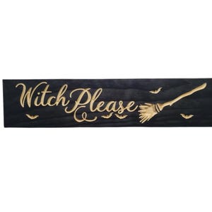 K&ouml;nnte beinhalten: Ein schwarzes Holzschild mit dem Text "Witch Please" in goldenen Lettern. Ein goldener Besen und Flederm&auml;use sind ebenfalls in das Schild geschnitzt.