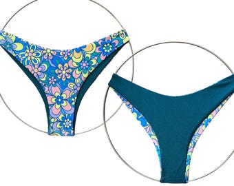 Pode incluir: Duas peças de biquíni, uma com estampa floral e a outra de cor azul-esverdeada sólida.