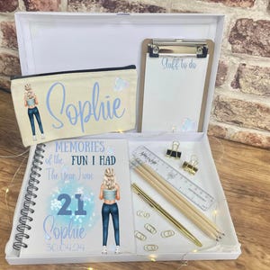 May include: A white gift box containing a pencil case, notebook, clipboard, and stationery. The pencil case and notebook feature a cartoon illustration and the name "Sophie". The notebook reads "Memories of the Fun I Had The Year I Was 21 Sophie 30.04.04".