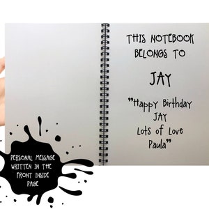 May include: A spiral-bound notebook with the text "THIS NOTEBOOK BELONGS TO JAY" and a birthday message. A black ink blotch with the text "PERSONAL MESSAGE WRITTEN IN THE FRONT INSIDE PAGE" is on the left.