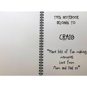 May include: A white notebook with a black spiral binding. The front cover has the text "THIS NOTEBOOK BELONGS TO CRAIG" and the message "Have lots of fun making memories Love from Mum and Dad xx".