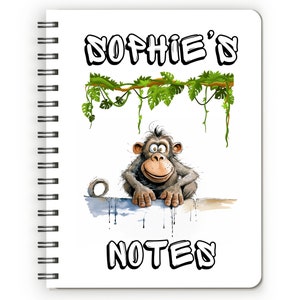 May include: A white spiral notebook with a cartoon monkey peeking over the top. The notebook has the text "Sophie's Notes" printed on the front.