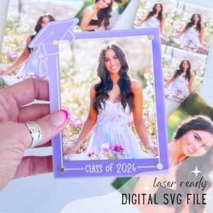 May include: A graduation photo frame in a light purple color, with a matching mortarboard design. The frame holds a photo of a woman in a floral dress. The text "CLASS OF 2026" is printed at the bottom. The words "laser ready DIGITAL SVG FILE" are also visible.