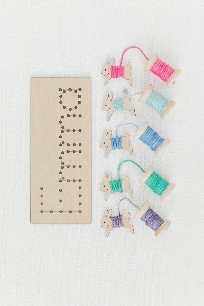 May include: Wooden bunny shaped lacing cards with colorful yarn spools. The card has the word "Bunny" spelled out with holes for lacing.