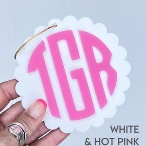 Peut inclure: Ornement rond blanc &agrave; festons avec un monogramme "TGR" rose vif au centre.  BLANC & ROSE VIF.