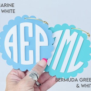 Puede incluir: Dos adornos redondos de madera con forma de fest&oacute;n con letras blancas que deletrean "AEP" y "ML". El adorno de la izquierda es azul claro con el texto "MARINE & WHITE" encima. El adorno de la derecha es turquesa con el texto "BERMUDA GREEN & WHITE" debajo.