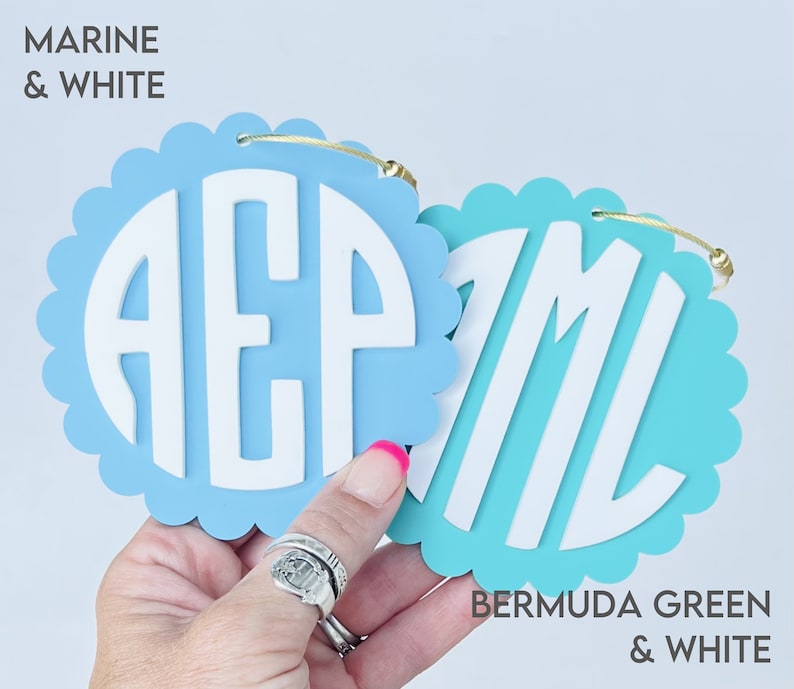 Puede incluir: Dos adornos redondos de madera con forma de fest&oacute;n con letras blancas que deletrean "AEP" y "ML". El adorno de la izquierda es azul claro con el texto "MARINE & WHITE" encima. El adorno de la derecha es turquesa con el texto "BERMUDA GREEN & WHITE" debajo.