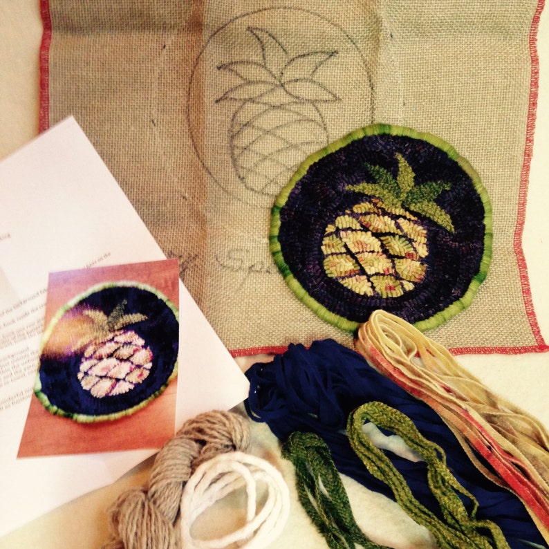 May include: A close-up of a needlepoint kit featuring a pineapple design. The kit includes a canvas, yarn, and instructions.