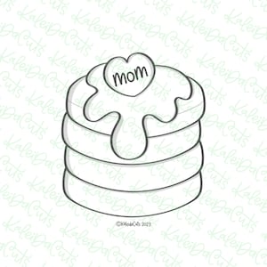 May include: A black and white line drawing of a stack of pancakes with a heart-shaped candy on top that says "Mom". The pancakes have a drizzle of syrup on top.