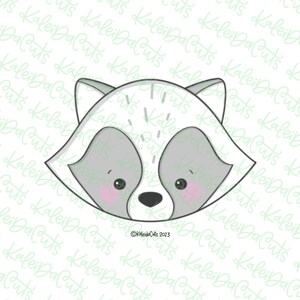May include: A cartoon raccoon face cookie cutter with a gray nose and black eyes. The raccoon has pink cheeks and is peeking out from behind a white background.