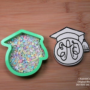 May include: Green plastic cookie cutter shaped like a graduation cap with sprinkles inside.  A white outline of a graduation cap with a monogram inside is also shown.