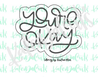 May include: A black and white cookie cutter in the shape of a cloud with the words "You're Okay" written in a cursive font.