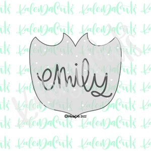 May include: A gray cookie cutter in the shape of a tulip with the name "emily" written in black inside. The cutter has a white background with small white dots.