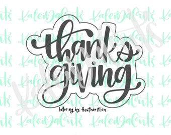 May include: A black and white cookie cutter in the shape of the word "thanksgiving" in a cursive font. The text "lettering by: Heather Allen" is below the word. The cookie cutter is for baking.