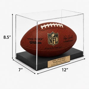 May include: A brown leather Wilson NFL football inside a clear acrylic display case with a black base. The case measures 12 inches wide, 7 inches deep, and 8.5 inches high. A gold plaque on the base reads: FREE ENGRAVING No Character Limit Keepsakes Under Glass.