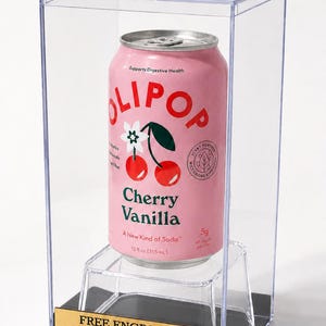 May include: A 12 fl oz aluminum can of Olipop Cherry Vanilla soda displayed inside a clear rectangular acrylic case. The pink can features a cherry graphic and text. A gold-colored plaque at the base reads: FREE ENGRAVING NO CHARACTER LIMIT Keepsakes Under Glass.