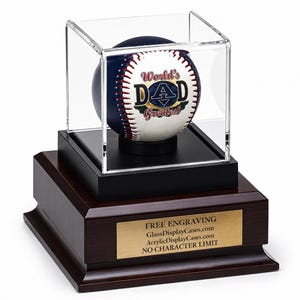 May include: A baseball with a dark blue and white surface featuring the text World's Greatest DAD, enclosed in a clear acrylic display case on a dark wood base with a gold plaque reading FREE ENGRAVING GlassDisplayCases.com AcrylicDisplayCases.com.