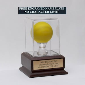 May include: A yellow ball displayed in a clear acrylic cube on a wooden base. The base has a brass plaque that reads "FREE ENGRAVING GlassDisplayCases.com NO CHARACTER LIMIT".