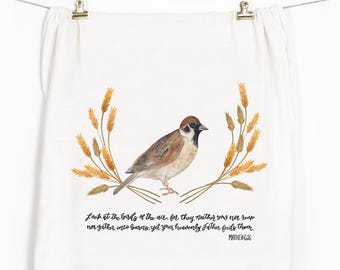 May include: A white tea towel with a watercolor illustration of a sparrow perched on a branch of wheat. The text "Look at the birds of the air, for they neither sow nor reap nor gather into barns, yet your heavenly Father feeds them. Matthew 6:26" is printed below the illustration.