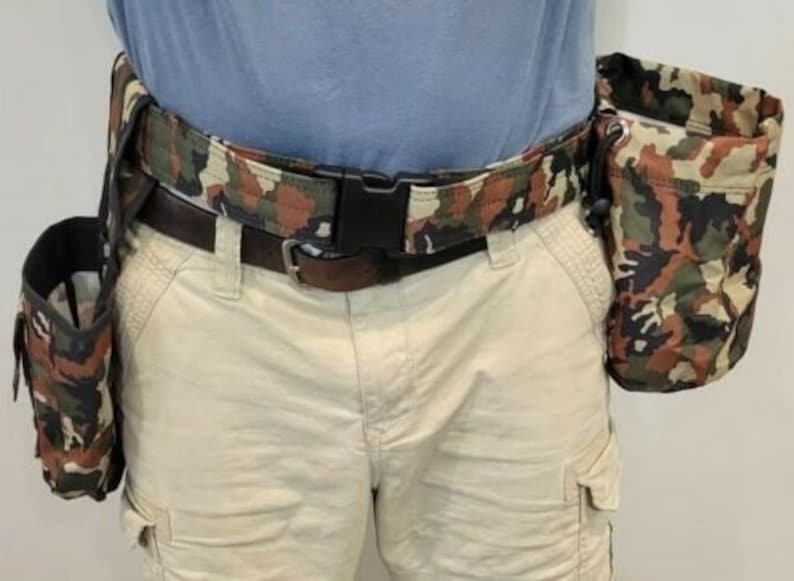 May include: A camouflage-patterned utility belt with multiple pouches. The belt is made of a durable fabric and has a metal buckle. The pouches are also made of camouflage fabric and have drawstrings.