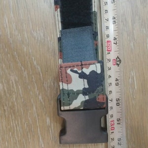 May include: A black and camouflage patterned belt with a black plastic buckle. The belt is 48 inches long.