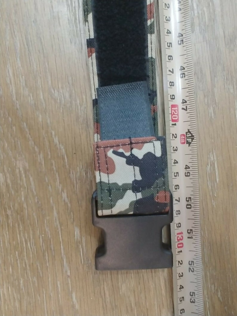 May include: A black and camouflage patterned belt with a black plastic buckle. The belt is 48 inches long.