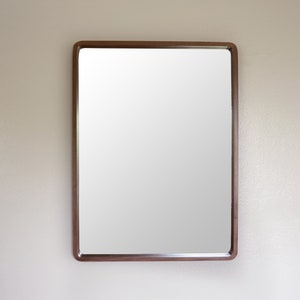 Puede incluir: Un espejo rectangular con un marco de madera marr&oacute;n.