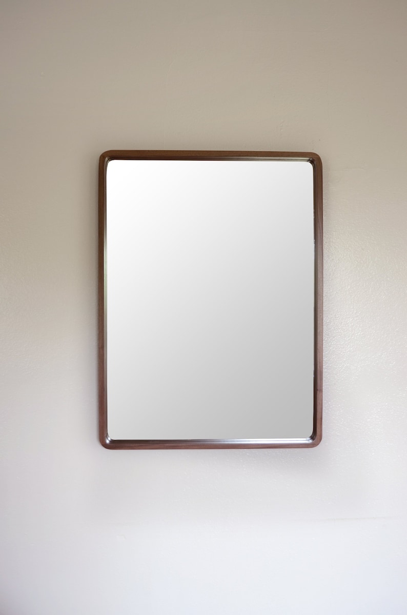 Puede incluir: Un espejo rectangular con un marco de madera marr&oacute;n.
