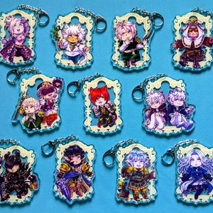 Könnte beinhalten: Set mit 10 bunten Anime-Charakter-Schlüsselanhängern. Jeder Schlüsselanhänger zeigt einen anderen Charakter in einem dekorativen Rahmen mit goldener Verzierung. Die Charaktere sind in verschiedenen Posen und Ausdrücken dargestellt.