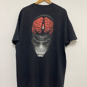 Op de afbeelding: Zwart T-shirt met een grafische print van een brein op een gezicht.
