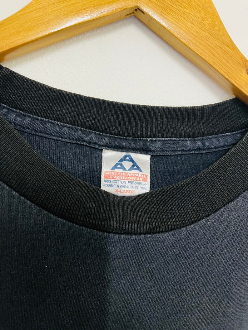 May include: A black t-shirt with a white tag that reads "Alstyle Apparel & Activewear 100% Cotton Pre-Shrunk Assembled in Mexico from US Fabric X-Large"