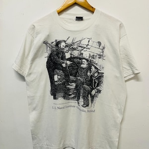 May include: White t-shirt featuring a black and white illustration of three men on a ship. The text "U.S. Naval Institute Annapolis, Maryland" is printed below the illustration.