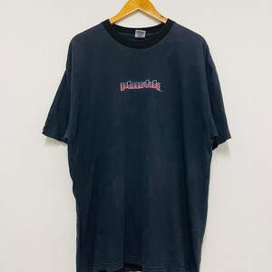 May include: Black t-shirt with a red and blue "Plastik" logo printed on the front.