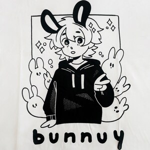 Puede incluir: Ilustraci&oacute;n en blanco y negro de un conejo de dibujos animados con una sudadera con capucha y rodeado de otros conejos. El texto "bunny" est&aacute; escrito debajo de la imagen.