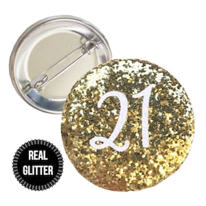 May include: Gold glitter button with the number 21 in white lettering. The button has a pin back.