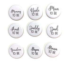 May include: Nine white round buttons with black text. The text on the buttons reads: "Mommy to Be", "Uncle to Be", "Mom to Be", "Aunt to Be", "Daddy to Be", "Dad to Be", "Grandma to Be", "Papa to Be", and "Nana to Be".