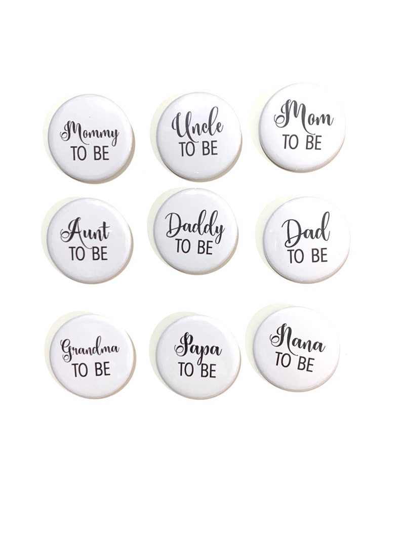 May include: Nine white round buttons with black text. The text on the buttons reads: "Mommy to Be", "Uncle to Be", "Mom to Be", "Aunt to Be", "Daddy to Be", "Dad to Be", "Grandma to Be", "Papa to Be", and "Nana to Be".