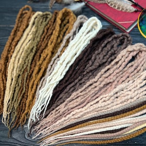 Dreads de lã encaracolada. Castanho, loiro, bege, castanho-avermelhado, ruivo. Dreadlocks de ponta dupla ou ponta simples. Cachos de lã. Cachos ondulados. Dreads personalizados