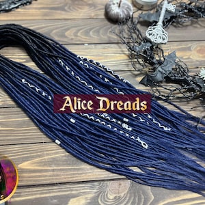 May include: Dark blue and black synthetic dreadlocks with white accents. The dreadlocks are arranged in a loose braid and are lying on a wooden surface.